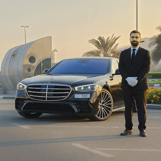 Chauffeur im Anzug neben einer schwarzen Limousine am Flughafen